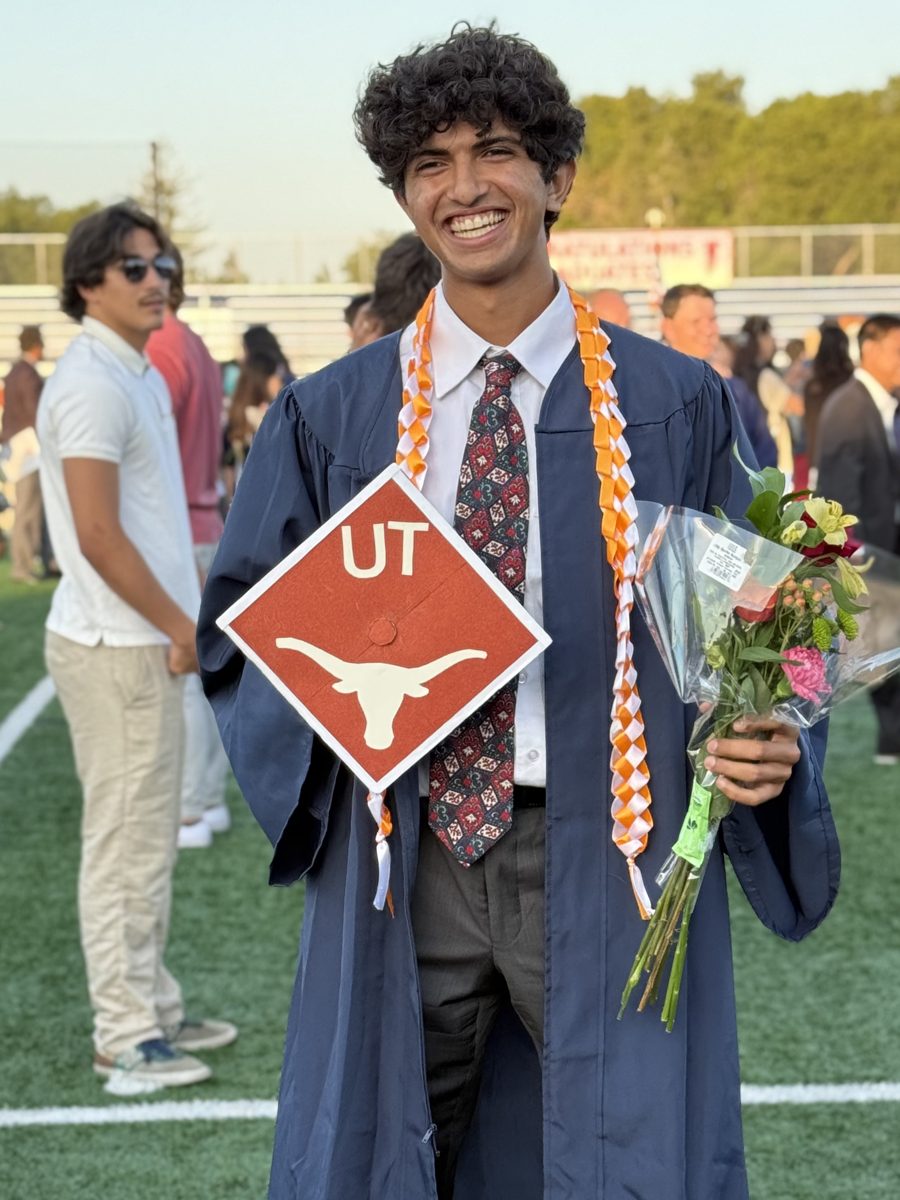 Adi Hebbalae at his high school graduation, holding a UT Austin sign